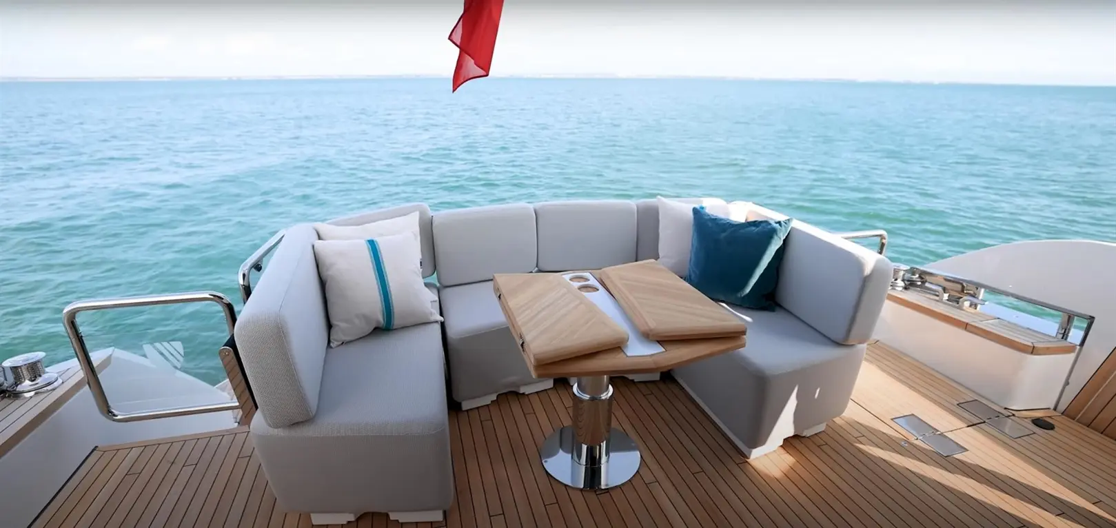 Stylish boat seating area with a wooden table, cushions, and a view of calm waters, perfect for relaxation and leisure.